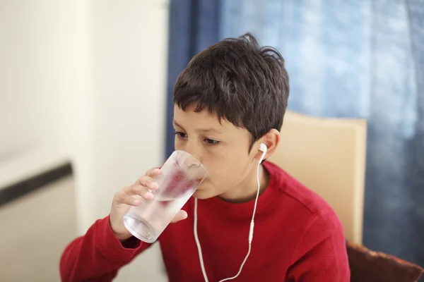 Young boy drinking from a glass of water — Stock Photo, Image