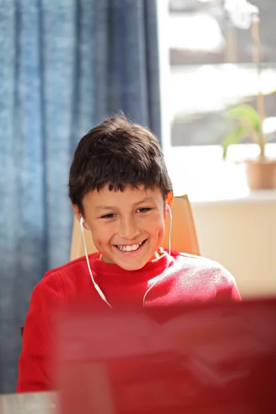 Молодой улыбающийся мальчик смотрит в компьютер — стоковое фото