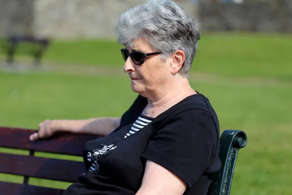 Yaşlı bayan dışında bir bankta rahatlatır — Stok fotoğraf