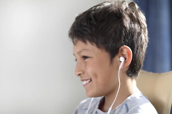 Młody chłopak uśmiechający się z słuchawki — Zdjęcie stockowe