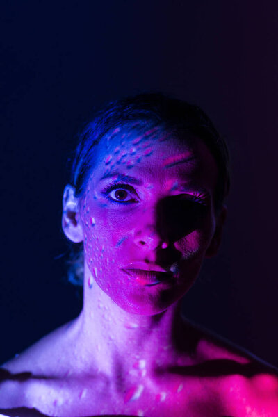 Creative portrait of a woman illuminated with colored lights on dark background.
