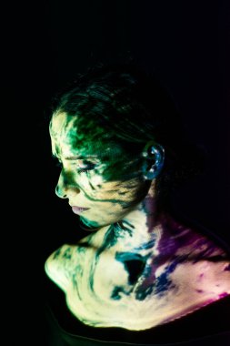 Koyu arkaplanda renkli ışıklarla aydınlatılmış yaratıcı bir kadın portresi..