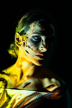 Koyu arkaplanda renkli ışıklarla aydınlatılmış yaratıcı bir kadın portresi..