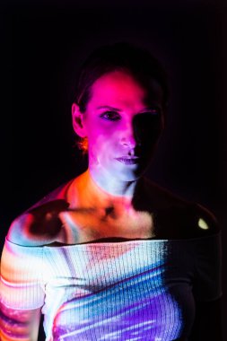 Koyu arkaplanda renkli ışıklarla aydınlatılmış yaratıcı bir kadın portresi..