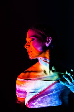 Koyu arkaplanda renkli ışıklarla aydınlatılmış yaratıcı bir kadın portresi..