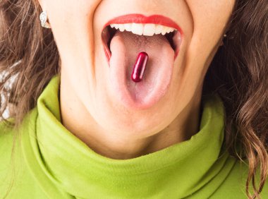 Üzerinde kırmızı hap olan bir kadının dili..