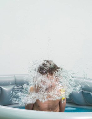 Bir çocuğun kafasının üstünde patlayan bir su balonu. Su oyunları yaz sıcağını daha dayanılır kılmak için idealdir..