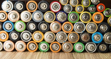 Ahşap bir masaya düzgünce yerleştirilmiş bataryalar. Geri dönüşüm ve çevre bakımı kavramı.