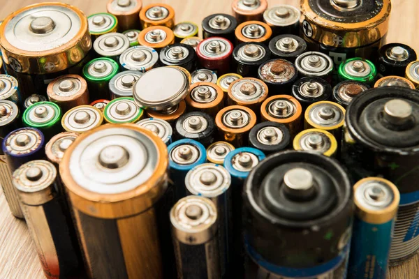 Ahşap bir masaya düzgünce yerleştirilmiş bataryalar. Geri dönüşüm ve çevre bakımı kavramı.