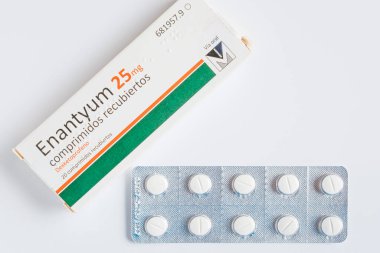 Arahal. Sevilla. İspanya. 2026, 30 Ocak. Bir kutu Enantyum (dexketoprofen) 25 mg anti-inflamatuar ilaç, beyaz arka planda, su toplayan tabletlerin yanında.
