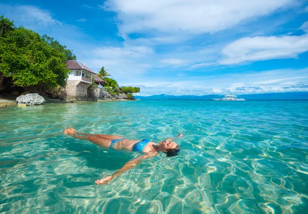 Junge Frau im Bikini entspannt auf dem Wasser liegend vor Hintergrund — Stockfoto