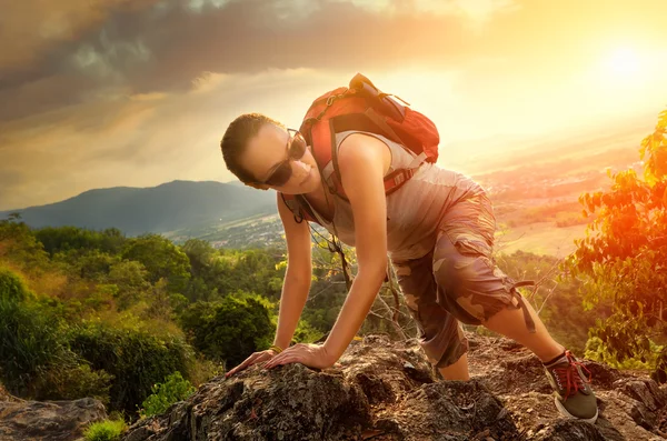 Flicka med en ryggsäck upp i bergen på en bakgrund av sunset — Stockfoto