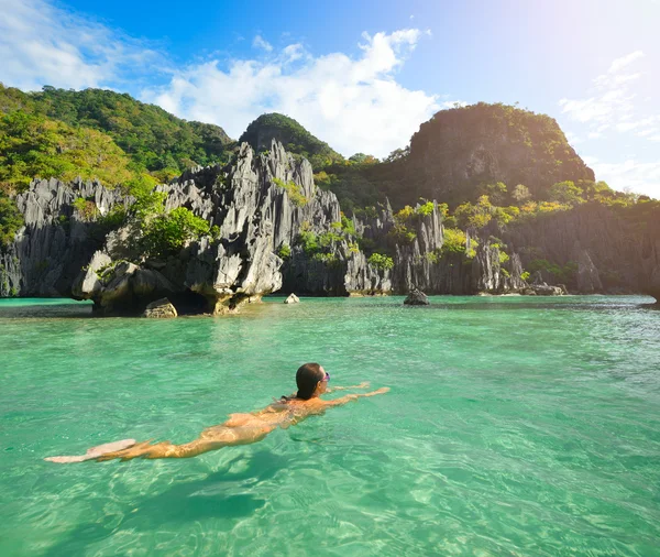 Счастливая женщина плавает в кристально чистой воде недалеко от островов — стоковое фото