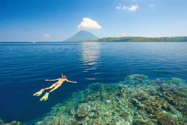 Perempuan snorkeling di perairan tropis yang jernih di latar belakang isl — Stok Foto