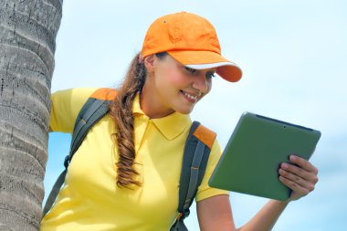 Side view of young woman in cap on the outdoor with  tablet comp clipart