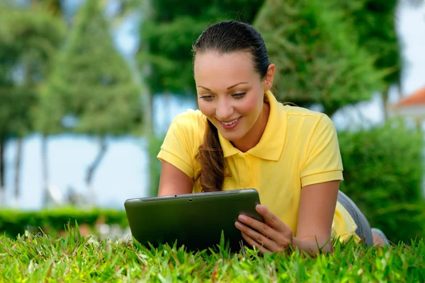 Young woman lying on the lawn with a tablet computer — Stock Photo, Image