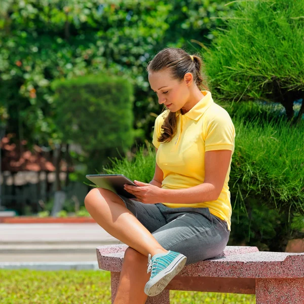 Afbeelding van elegante jonge meisje met een tablet pc, zittend op de worden — Stockfoto