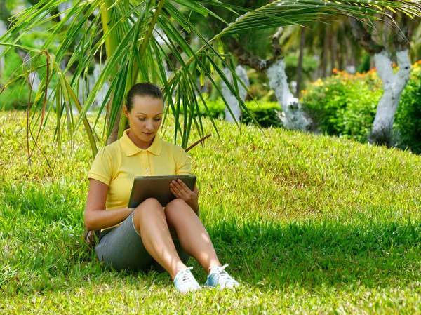 Mujer joven usando tableta al aire libre puesta en la hierba . —  Fotos de Stock