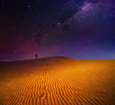 A backpacker is walking among sandy dunes under the starry sky clipart