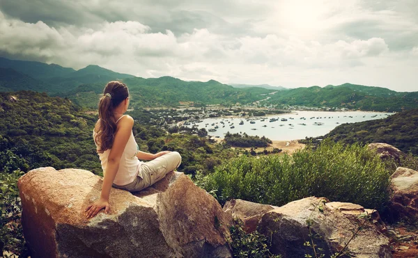 Woman traveler looks at the edge of the cliff on the  sea bay of — Stock Photo, Image