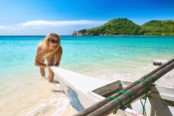 Glad ung kvinna ler hjälper till att dra båten till stranden. — Stockfoto