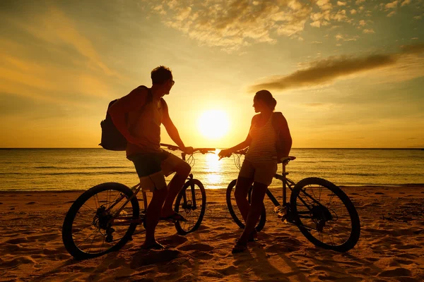 Couple touristes avec vélos regarder coucher de soleil. Silhouette personnes Photo De Stock