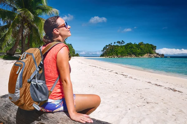 Joyeux jeune femme assis avec sac à dos sur la mer côtière et regardant à — Photo