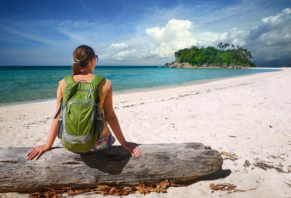 Jovem com mochila relaxante na costa e olhando para uma ilha — Fotografia de Stock