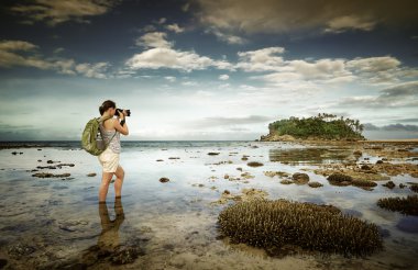 Standing in the sea water traveler woman with backpack taking a clipart