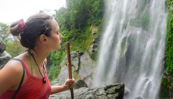 Fáradt, de boldog fiatal nő természetjáró látszó-on egy vízesés jungle — Stock Fotó