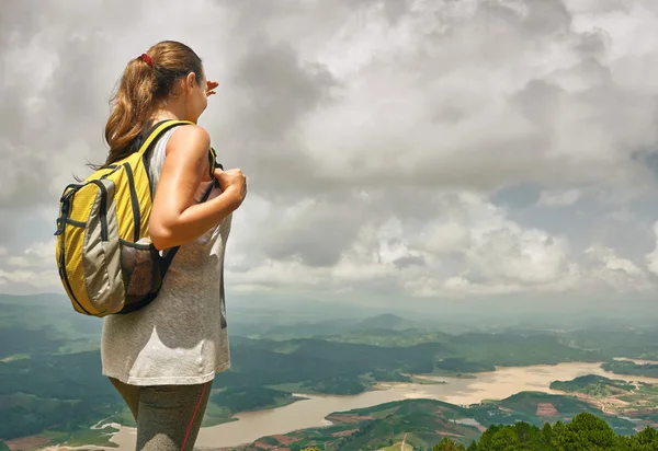 Jonge vrouw wandelaar met rugzak staande op de top van de berg — Stockfoto