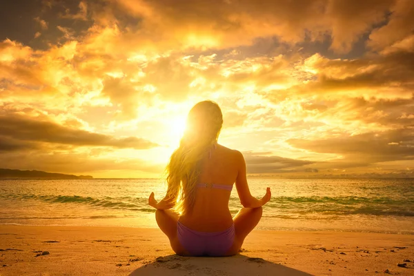 Jeune femme se relaxant en position lotus lors d'un beau coucher de soleil Images De Stock Libres De Droits