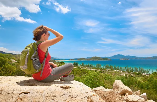 Tourist with backpack sit on a rock on clear sky background, loo — Stock Photo, Image