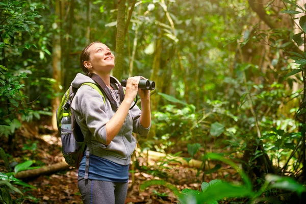 Excursionista observando a través de prismáticos aves silvestres en la selva . —  Fotos de Stock