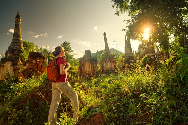 Backpacker traveling  with backpack and looks at sunset among an — Stock Photo, Image