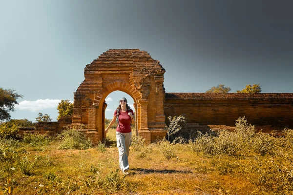 Young lady with a backpack out of the gates of the ancient ruins — Stock Photo, Image