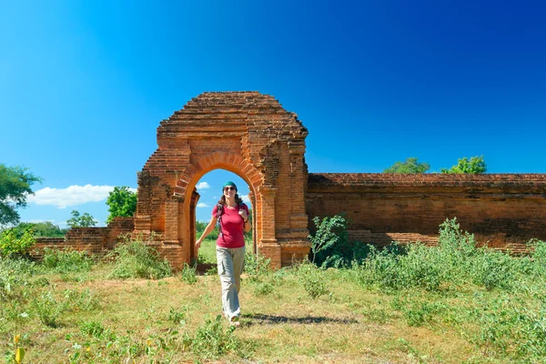 Jonge dame met een rugzak uit de poorten van de oude ruïnes — Stockfoto