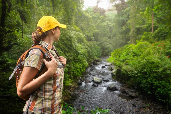 Woman hiker with backpack standing and enjoying rain forest and — Stock Photo, Image