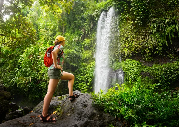 Junge Backpackerin blickt auf den Wasserfall im Dschungel. — Stockfoto