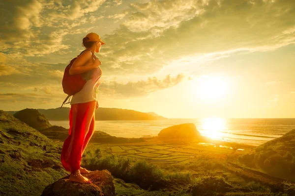 Turysta kobieta stojąc na górze i cieszyć zachód słońca nad morzem. — Zdjęcie stockowe
