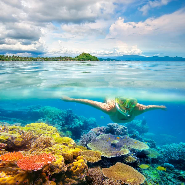 Женщина ныряет с маской в прозрачных тропических водах перед экзотическим островом — стоковое фото