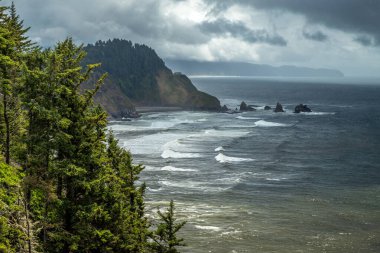 Yağmurlu bir günde Üç Kemerli Kayalar 'ın göz kamaştırıcı manzarası. Güneş ışığı bulutların arasından, Cape Meares, Oregon' dan geçmeye çalışıyor.