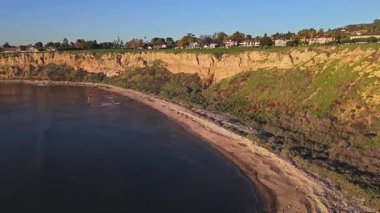 Güneş batarken, okyanusun üzerindeki engebeli kayalıkları ve evleri aydınlatan, nefes kesici Lunada Körfezi 'nin hava yörüngesi çekimi, Palos Verdes Evleri, Kaliforniya