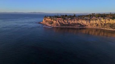 Güneş batarken Palos Verdes 'in nefes kesen sahili, okyanusun üzerindeki engebeli kayalıkları ve evleri aydınlatan, Palos Verdes Evleri, Kaliforniya