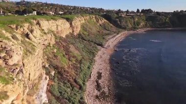 Güneş batarken, okyanusun üzerindeki engebeli kayalıkları ve evleri aydınlatan, nefes kesici Lunada Körfezi 'nin sinematik hava gösterimi, Palos Verdes Emlak, Kaliforniya