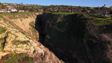 Güneş batarken, okyanusun üzerindeki engebeli kayalıkları ve evleri aydınlatan, nefes kesen Lunada Körfezi 'nin yüksek hava çekimi, Palos Verdes Evleri, Kaliforniya