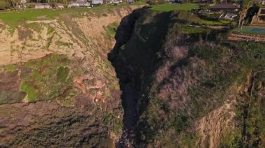 Güneş batarken, okyanusun üzerindeki engebeli kayalıkları ve evleri aydınlatan, nefes kesen Lunada Körfezi 'nin yüksek hava çekimi, Palos Verdes Evleri, Kaliforniya