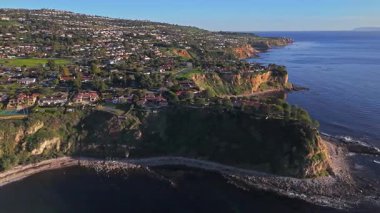 Güneş batarken Palos Verdes kıyı şeridinin nefes kesici yörünge çekimi okyanusun üzerindeki engebeli kayalıkları ve evleri aydınlatıyor, Palos Verdes Evleri, Kaliforniya