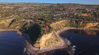 Güneş batarken Palos Verdes kıyı şeridinin nefes kesici yörünge çekimi okyanusun üzerindeki engebeli kayalıkları ve evleri aydınlatıyor, Palos Verdes Evleri, Kaliforniya