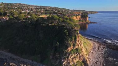 Güneş batarken Palos Verdes 'in nefes kesen sahili, okyanusun üzerindeki engebeli kayalıkları ve evleri aydınlatan hava çekimi Palos Verdes Emlak, Kaliforniya